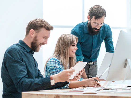 Eine Gruppe Teilnehmer sitzt in einer Umschulung vor dem Computer und erarbeiten eine Gruppenaufgabe.