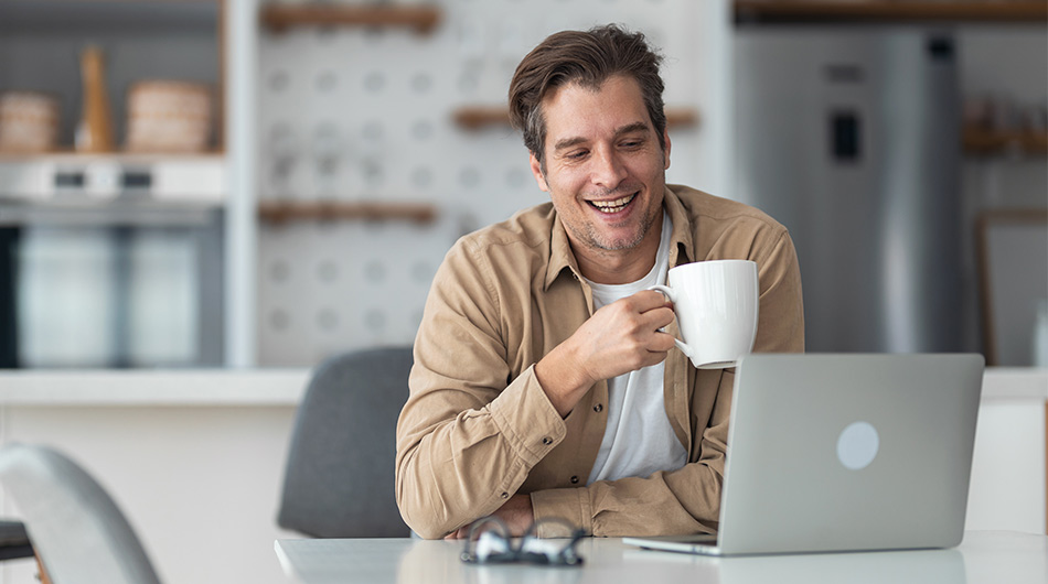 Zu sehen ist ein Trainer an seinem Arbeitsplatz, er sitzt mit einer Tasse in seiner Online-Weiterbildung.